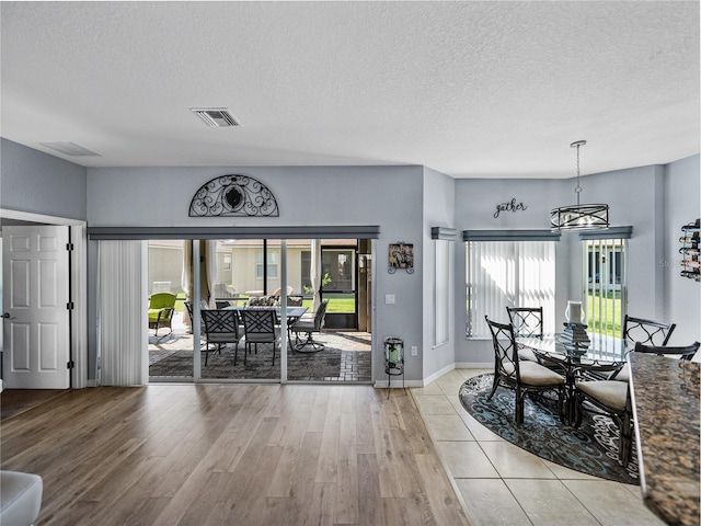 dining area with baseboards, a textured ceiling, visible vents, and wood finished floors