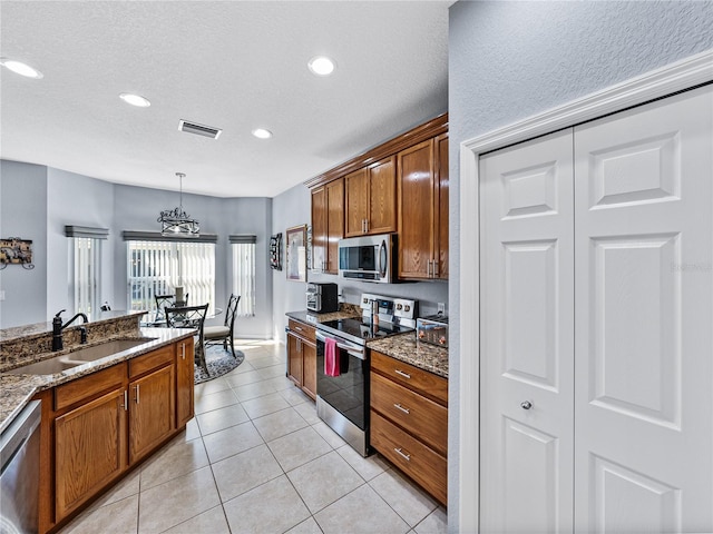 kitchen with appliances with stainless steel finishes, a sink, visible vents, and brown cabinets