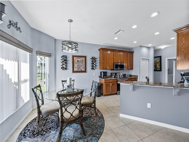 kitchen featuring brown cabinets, a breakfast bar, a peninsula, stainless steel appliances, and stone counters