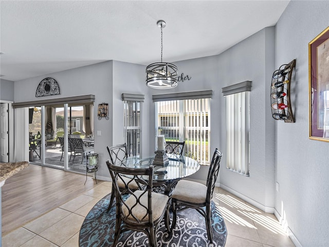 dining room with a notable chandelier, light tile patterned flooring, and baseboards