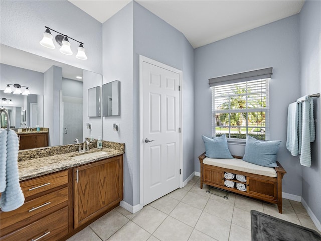 bathroom with tile patterned floors, two vanities, a sink, and baseboards