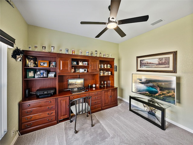 office space featuring baseboards, visible vents, ceiling fan, and light colored carpet