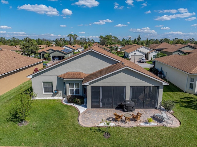 back of property featuring a yard, a sunroom, a residential view, and stucco siding