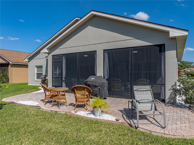 rear view of house featuring a patio area, stucco siding, a sunroom, and a yard