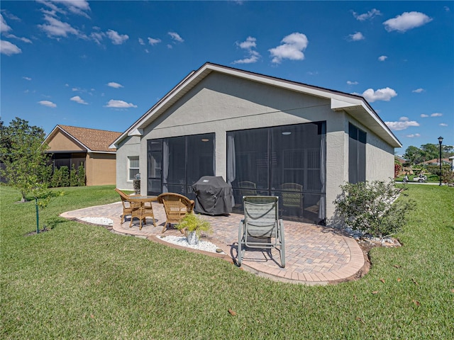 back of house featuring a yard, stucco siding, a sunroom, and a patio