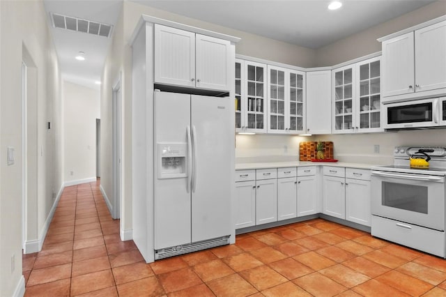 kitchen featuring white appliances, white cabinetry, visible vents, and light countertops