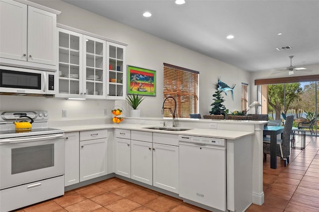 kitchen featuring white cabinets, white appliances, light countertops, and a sink