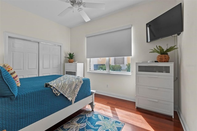 bedroom with a closet, wood finished floors, a ceiling fan, and baseboards