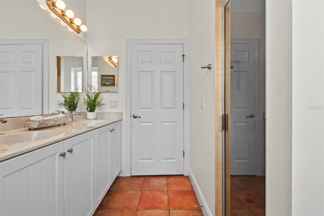 bathroom with tile patterned flooring, a sink, baseboards, and double vanity