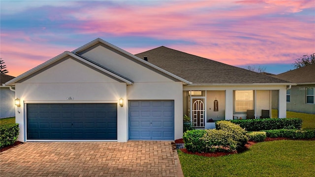 ranch-style house with a garage, decorative driveway, and stucco siding