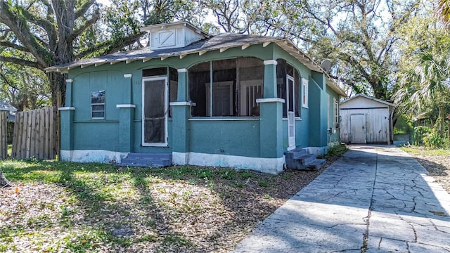 view of property exterior with entry steps, a storage shed, fence, and stucco siding