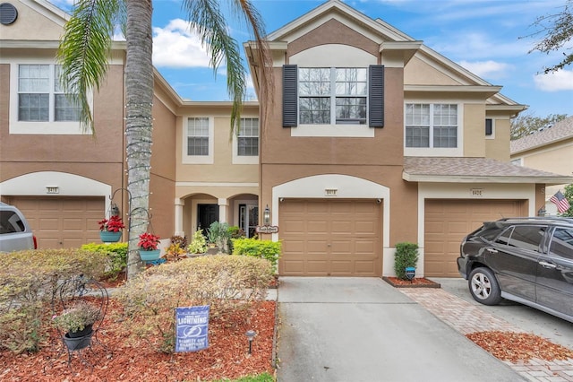 multi unit property featuring a garage, driveway, and stucco siding