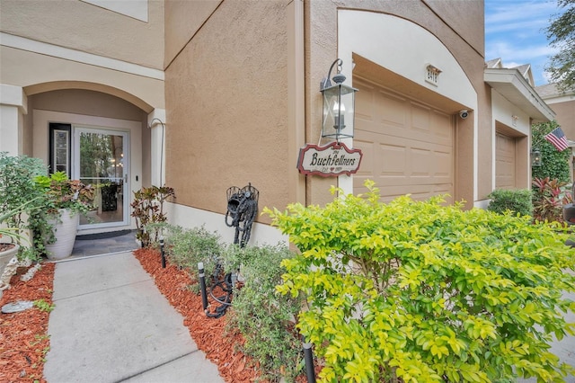 property entrance featuring a garage and stucco siding