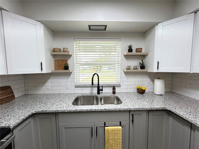 kitchen featuring white cabinetry, a sink, and light stone countertops