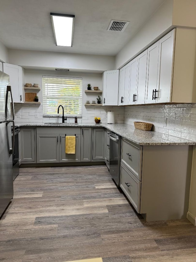 kitchen with visible vents, light stone countertops, gray cabinets, open shelves, and a sink