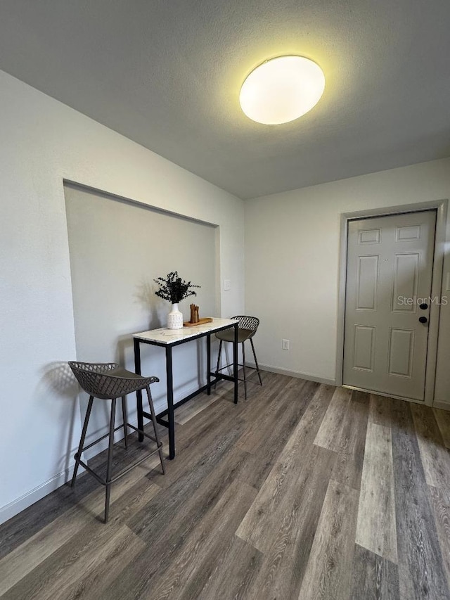 dining room featuring a textured ceiling, dark wood-style flooring, and baseboards