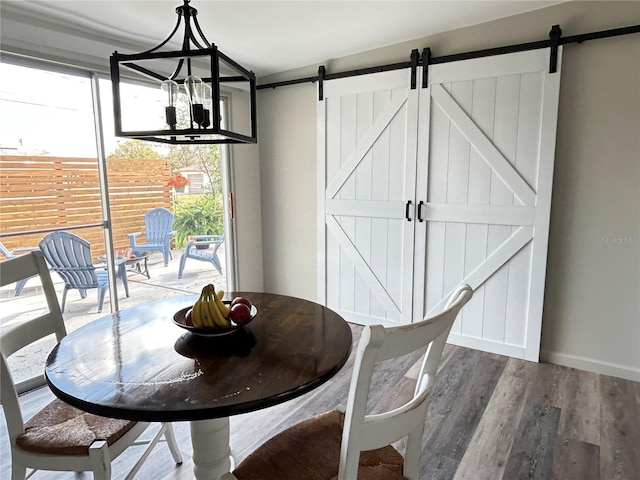 unfurnished dining area with wood finished floors, a healthy amount of sunlight, baseboards, and a barn door