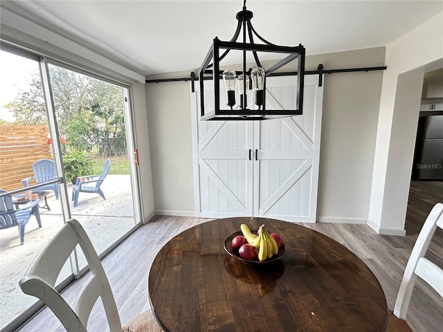 unfurnished dining area featuring wood finished floors, baseboards, and a barn door