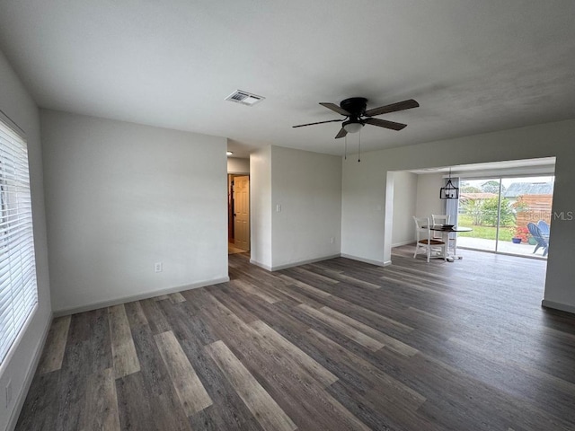 unfurnished room featuring a ceiling fan, visible vents, dark wood finished floors, and baseboards