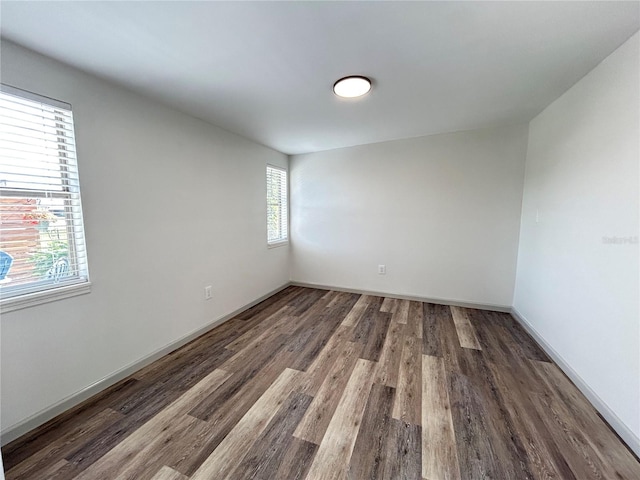 unfurnished room with baseboards and dark wood-style flooring