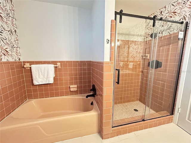 full bath with tile patterned flooring, a shower stall, a bath, and wainscoting