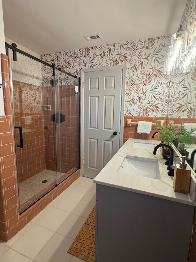 full bath with a sink, tile patterned floors, double vanity, a stall shower, and wallpapered walls