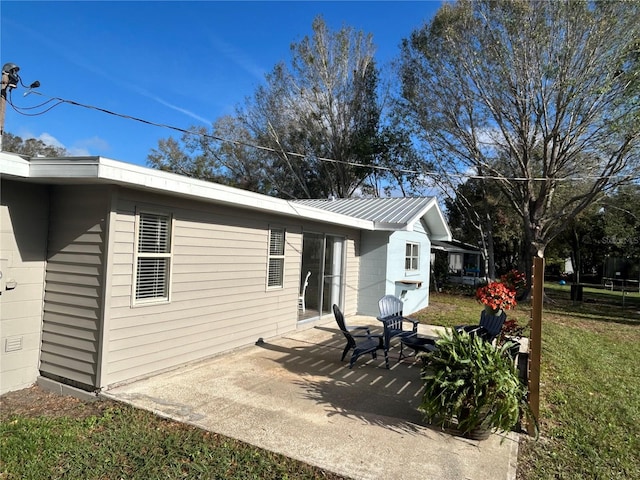 view of side of home featuring metal roof, a yard, and a patio area