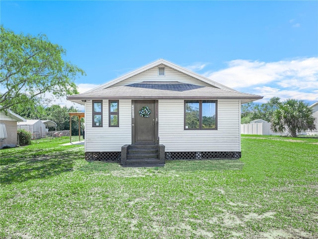 bungalow with entry steps, fence, and a front lawn