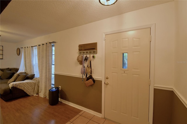 entryway with a textured ceiling, light tile patterned floors, and baseboards