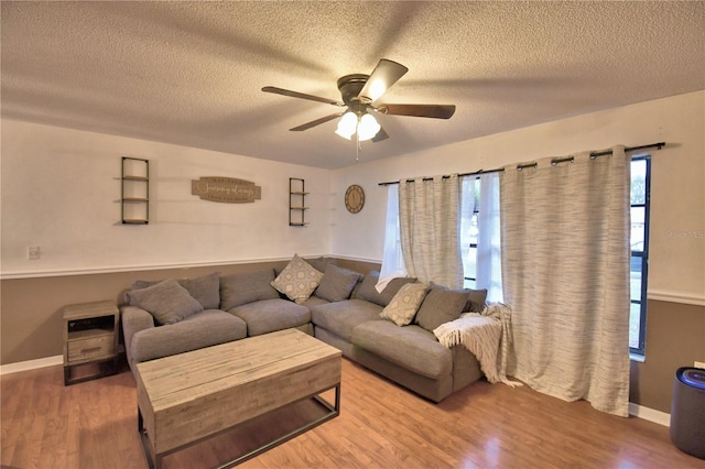 living area featuring ceiling fan, a textured ceiling, wood finished floors, and baseboards