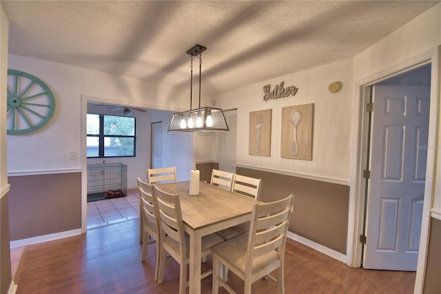 dining room with a textured ceiling, baseboards, and wood finished floors