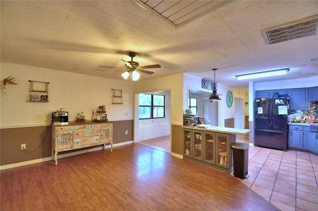 kitchen with pendant lighting, visible vents, light wood-style floors, freestanding refrigerator, and a peninsula