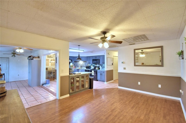 kitchen with light wood finished floors, decorative light fixtures, stainless steel electric stove, light countertops, and black microwave