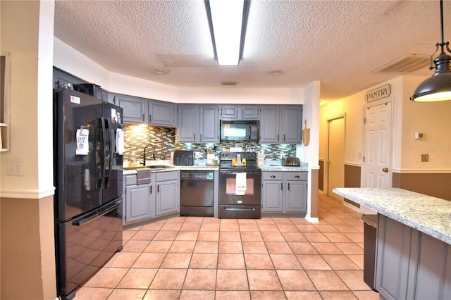 kitchen featuring light tile patterned floors, light countertops, decorative backsplash, black appliances, and pendant lighting