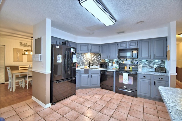 kitchen featuring black appliances, light tile patterned floors, decorative backsplash, and a sink