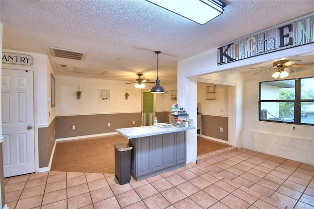 kitchen featuring visible vents, hanging light fixtures, a peninsula, light countertops, and light tile patterned flooring