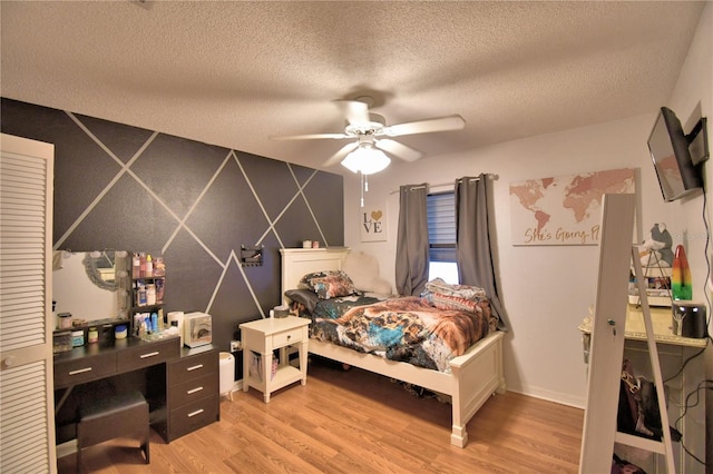 bedroom featuring light wood finished floors, ceiling fan, and a textured ceiling