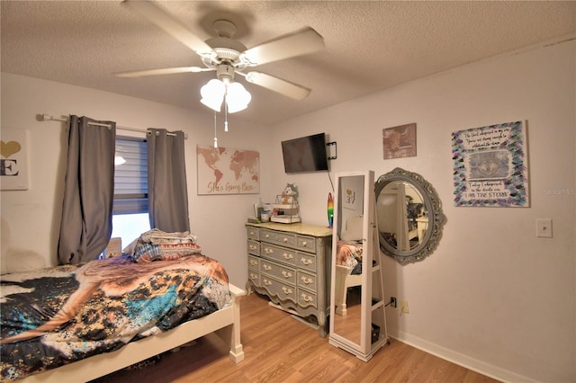 bedroom with light wood-type flooring, ceiling fan, baseboards, and a textured ceiling