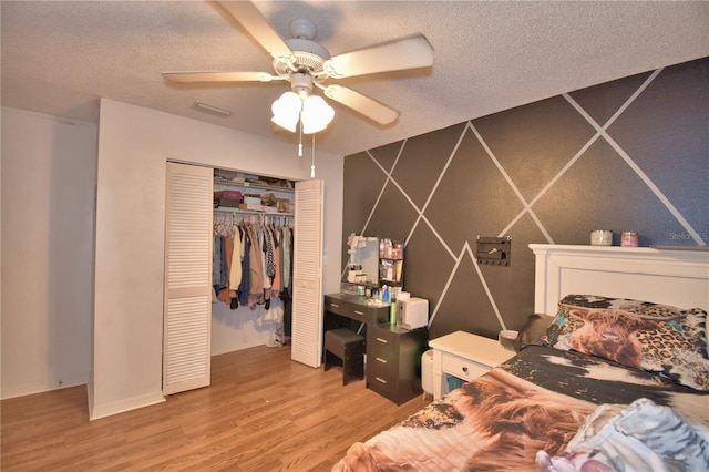 bedroom with a closet, visible vents, a ceiling fan, a textured ceiling, and wood finished floors