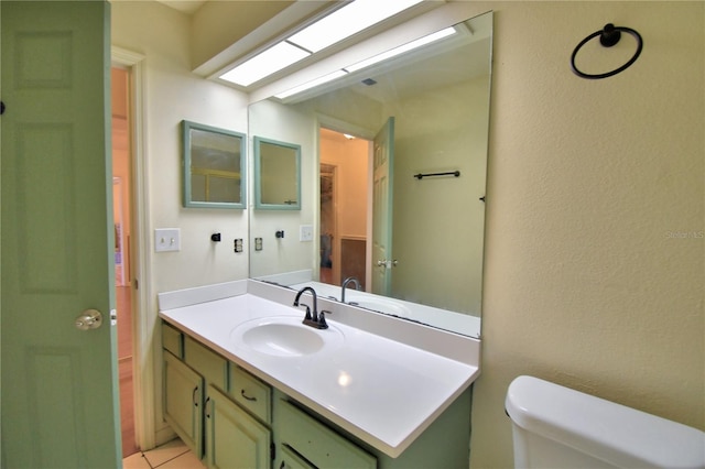 bathroom with a textured wall, vanity, and toilet