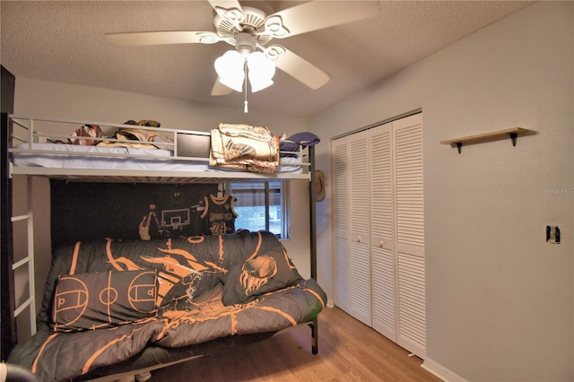 bedroom featuring a ceiling fan, a closet, a textured ceiling, and wood finished floors