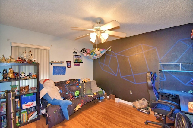 bedroom with a textured ceiling, wood finished floors, and a ceiling fan