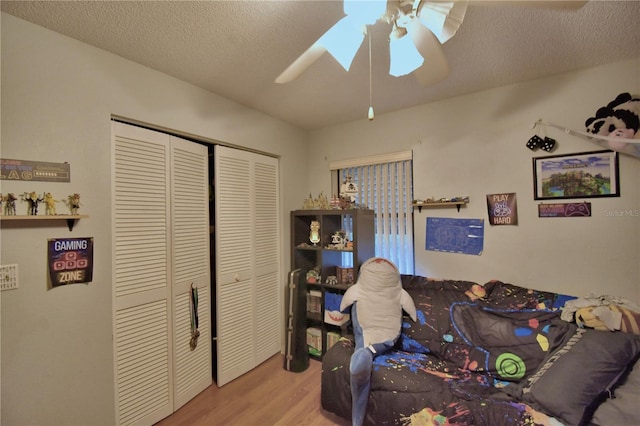 bedroom with light wood-style flooring, a textured ceiling, ceiling fan, and a closet