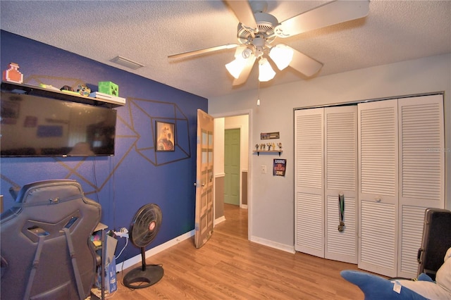 home office with a textured ceiling, wood finished floors, and visible vents