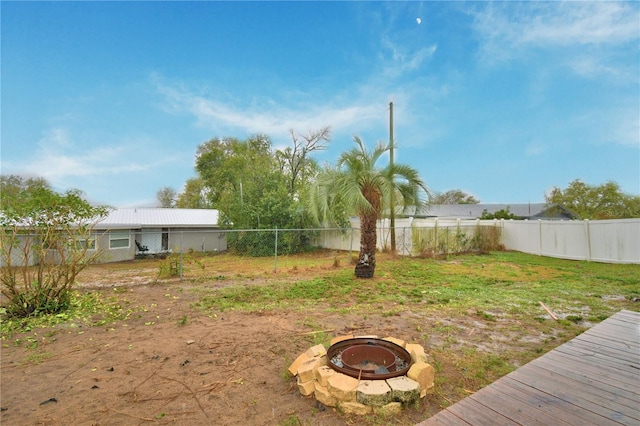 view of yard with a fire pit, a deck, and a fenced backyard