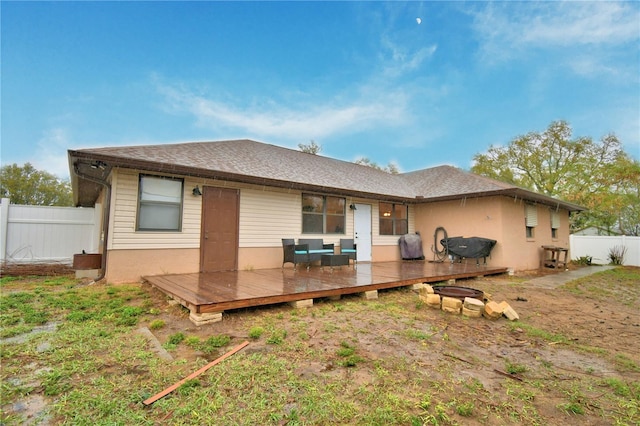 rear view of house with an outdoor fire pit, fence, a deck, and a shingled roof