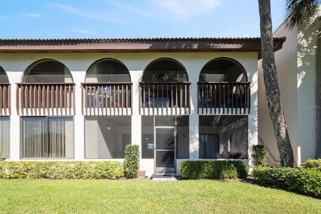 back of property featuring a yard and stucco siding