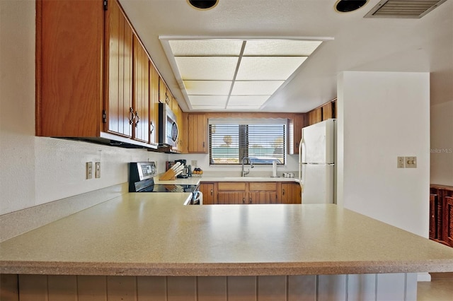 kitchen with stainless steel appliances, brown cabinetry, light countertops, and visible vents