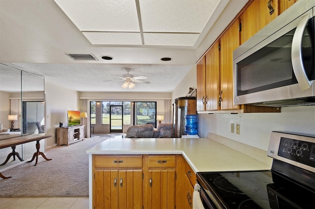 kitchen featuring stainless steel appliances, a peninsula, visible vents, open floor plan, and brown cabinetry