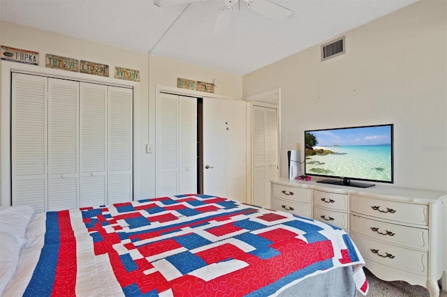 bedroom with visible vents, ceiling fan, and two closets